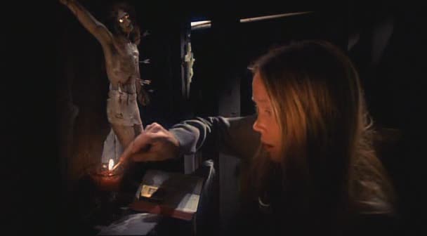 Carrie lights a candle in a prayer closet next to a statue of Jesus on a crucifix.